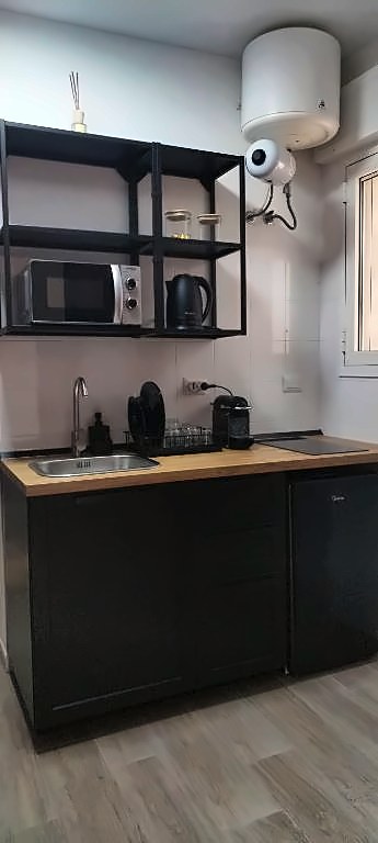 Angolo cottura con piano in legno, lavello, mensole in ferro, microonde e bollitore