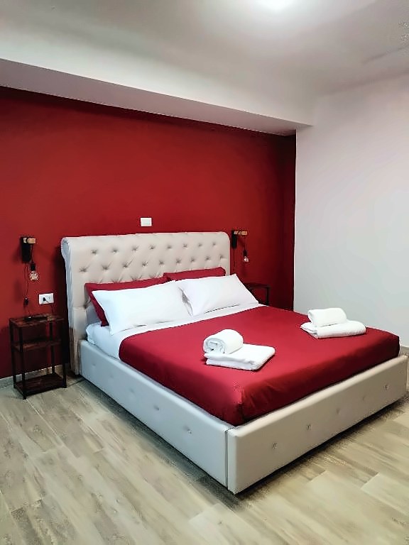 La camera con letto matrimoniale, comodini in ferro e parete bordeaux