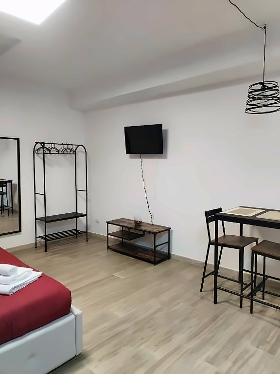 Vista del monolocale con appendiabiti, TV, mobile in legno e tavolo alto